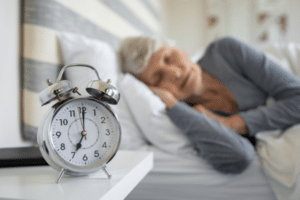senior woman sleeping next to clock